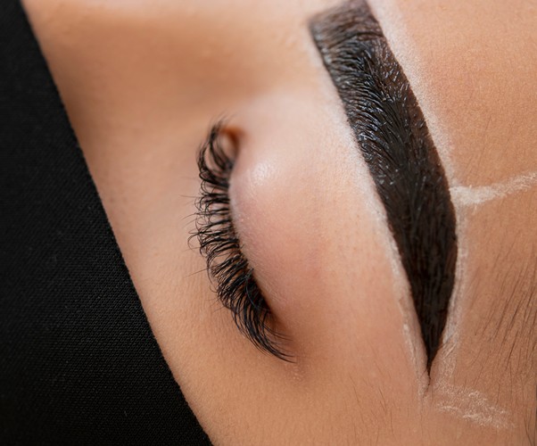 Beautician performing a microblading treatment on a client's eyebrows